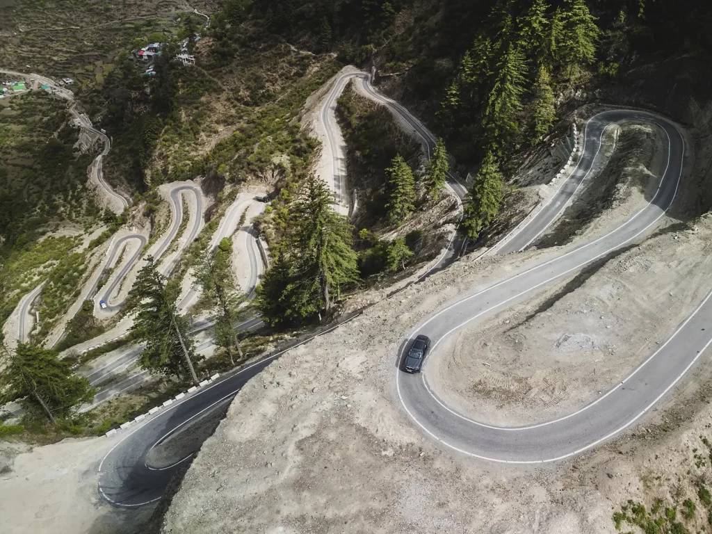 Drone image showcasing a car on rugged roads heading to Adi Kailash and Om Parvat, featuring automotive photography.
